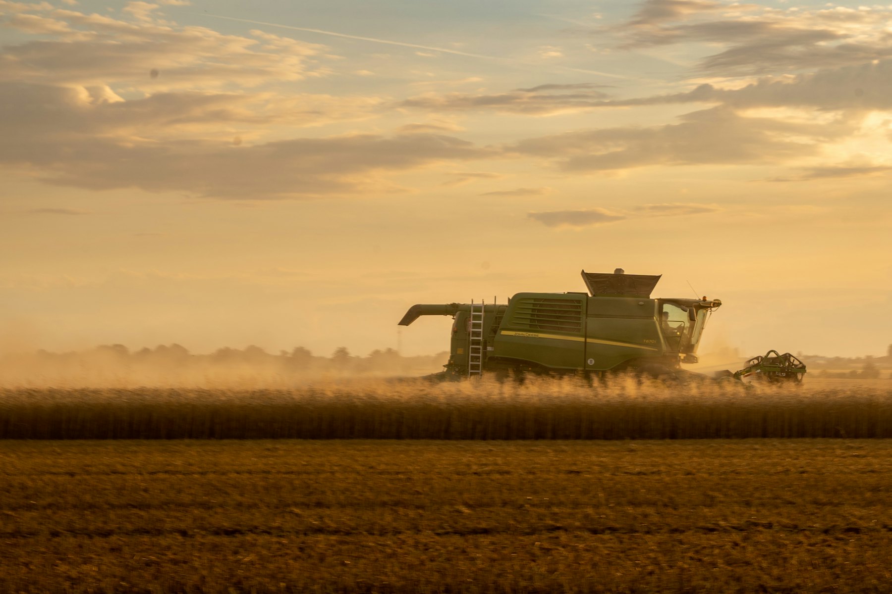 A combine harvester cutting through a grain field, panned so the machine is sharp against blurred motion