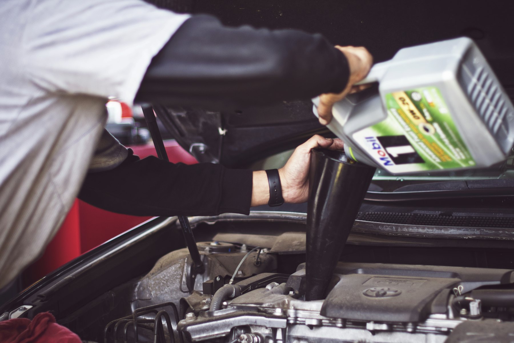 Motor oil being poured into an open engine bay