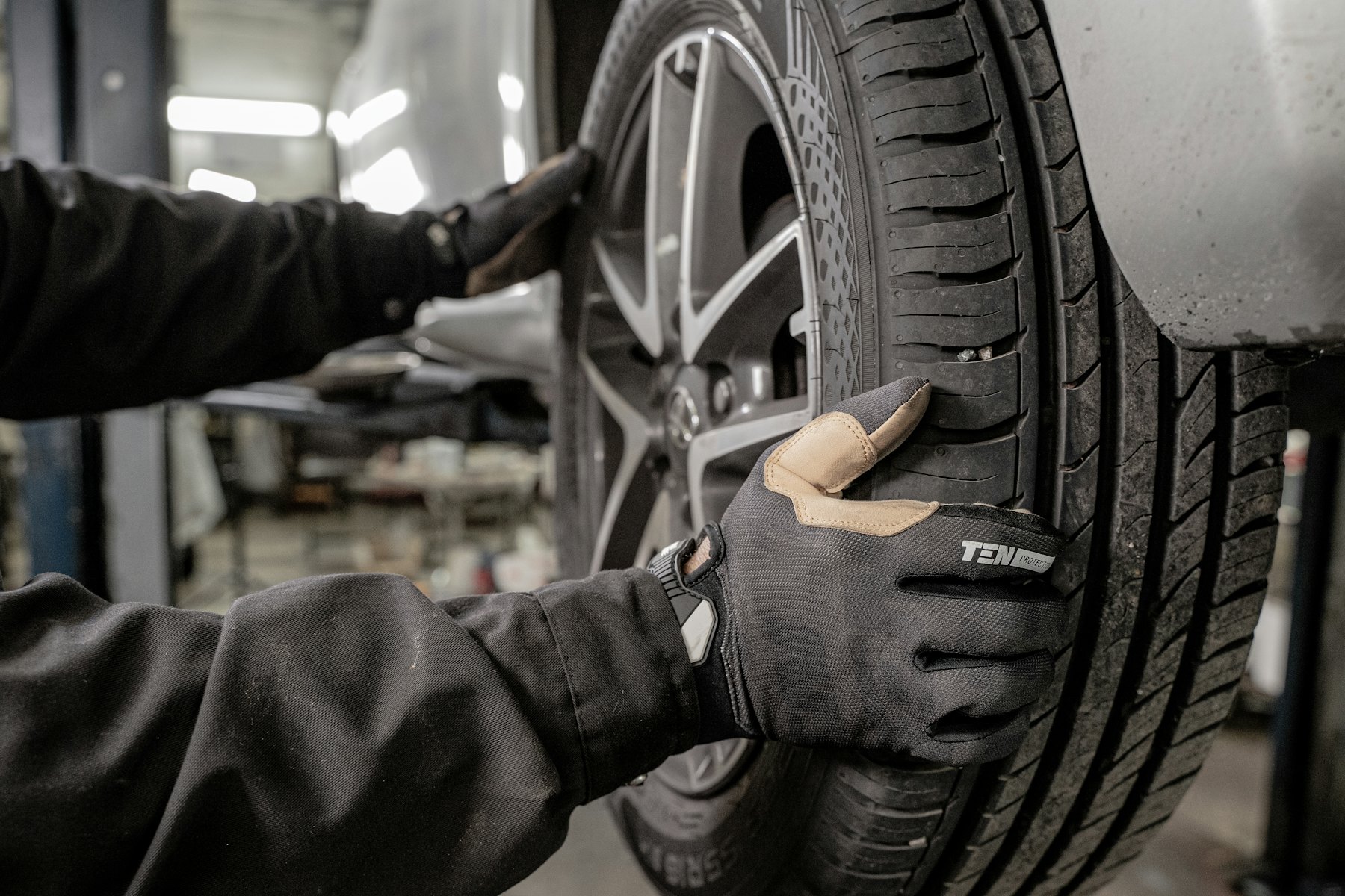 A gloved mechanic working on a wheel and tire in a garage bay
