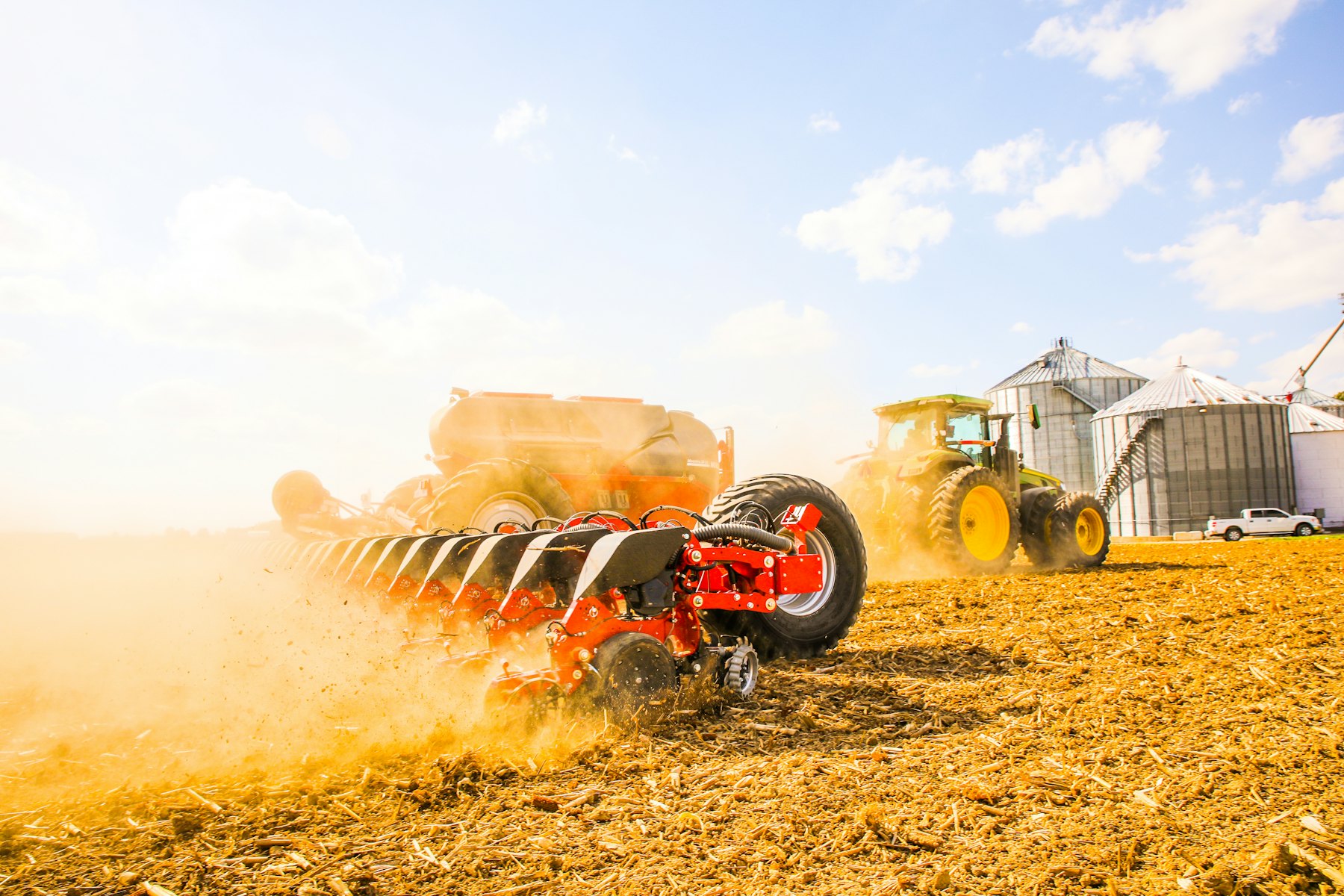 A tractor working across a cut hay field under an open blue sky